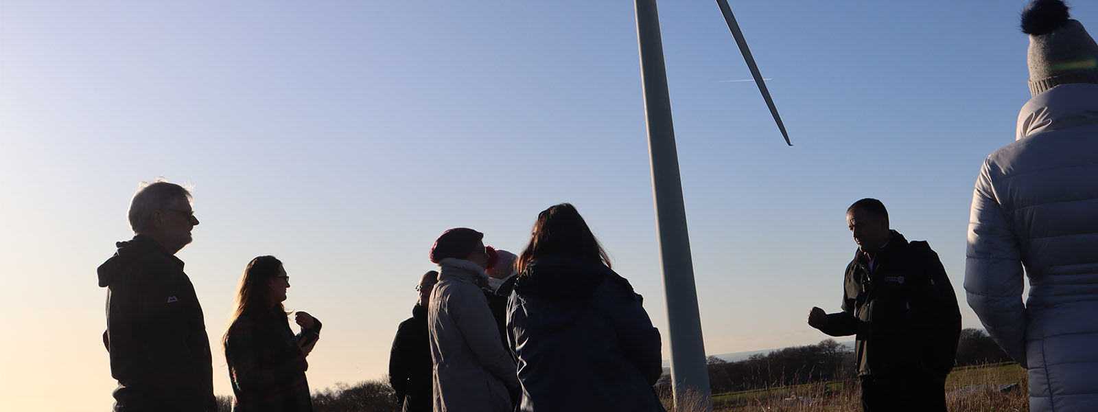 山ּ's wind turbine with people attending a talk on sustainability.